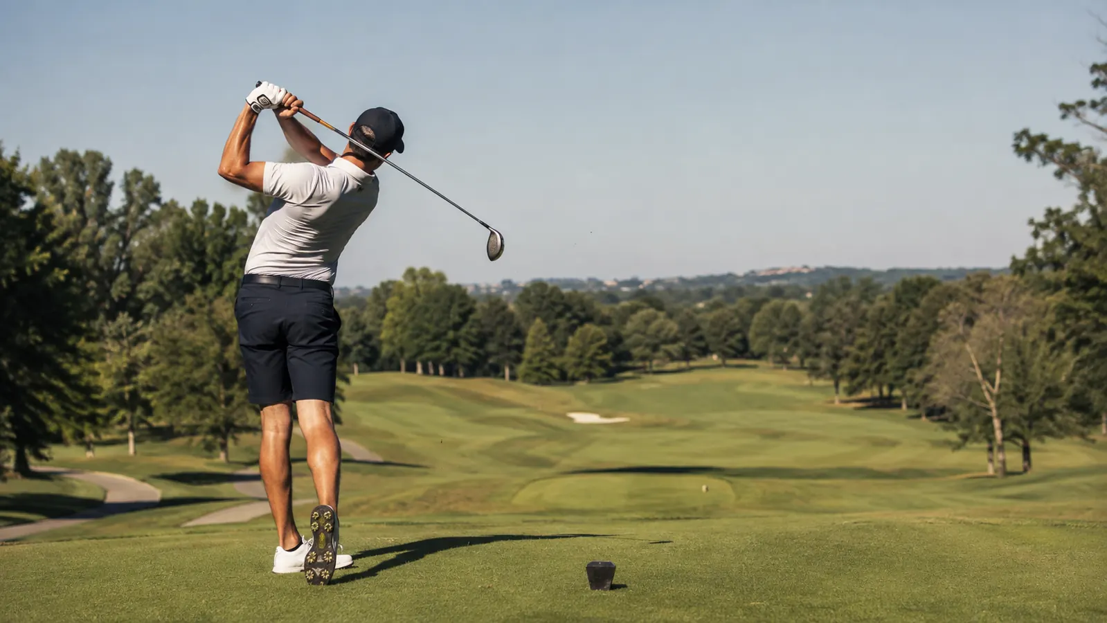 Golfer teeing off confidently on a sunny fairway after a pre-round swing trainer warmup