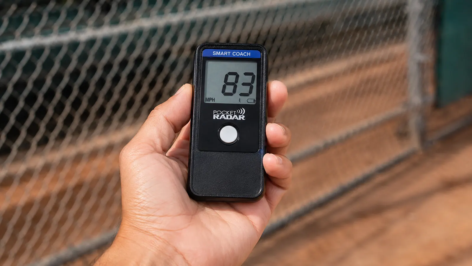 Hand holding the Pocket Radar Smart Coach up to check a velocity reading after a pitch