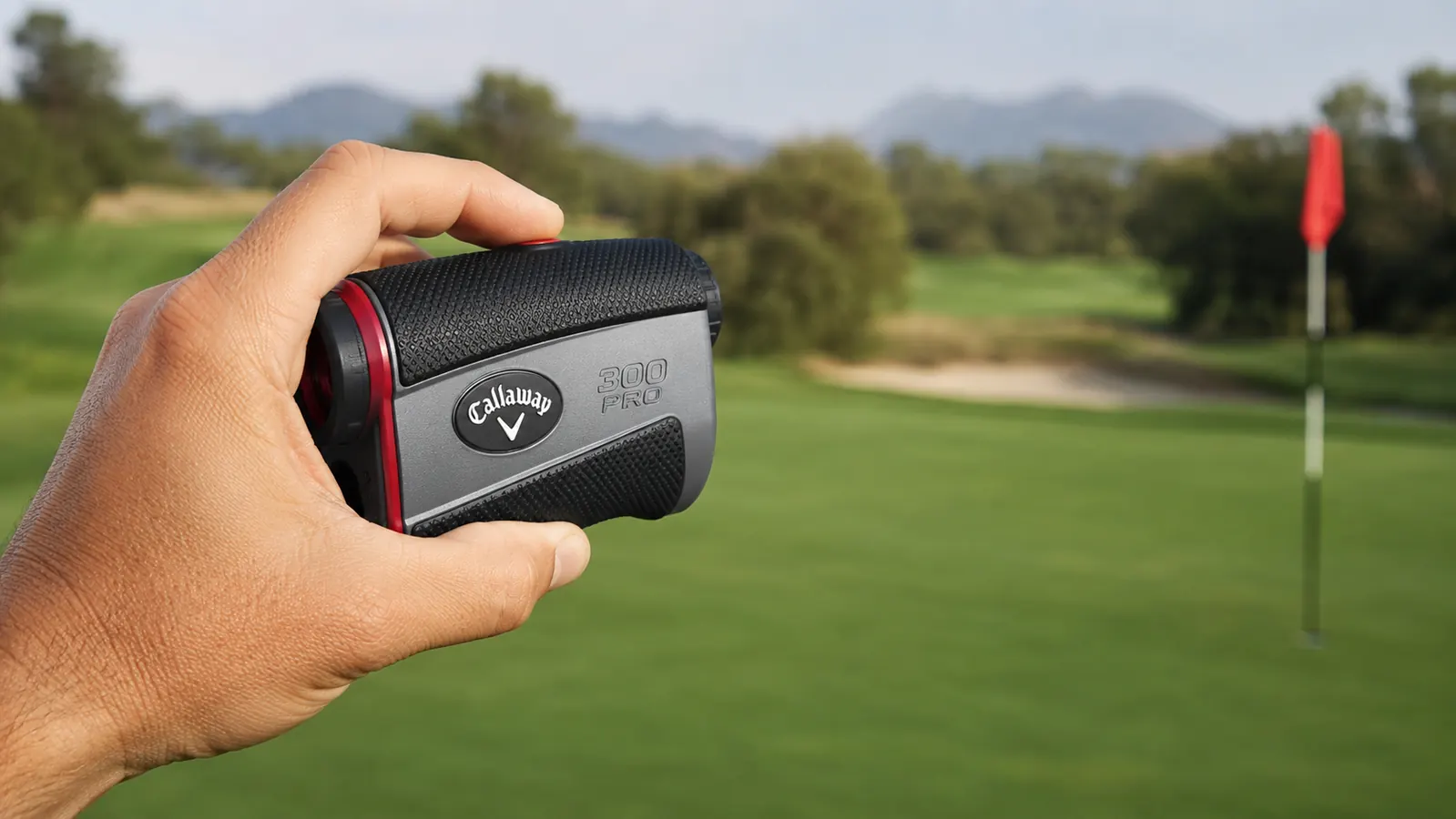 Close-up of a hand holding the Callaway 300 Pro rangefinder aimed at a distant flag