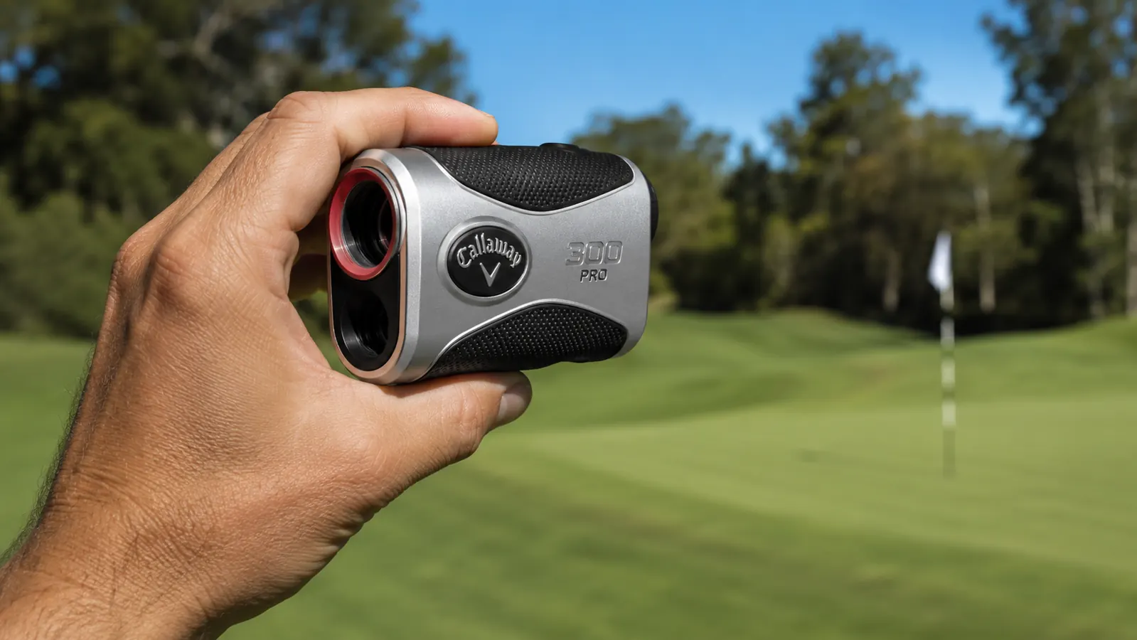 Hand holding the Callaway 300 Pro rangefinder up to sight a flag on a par-3 hole