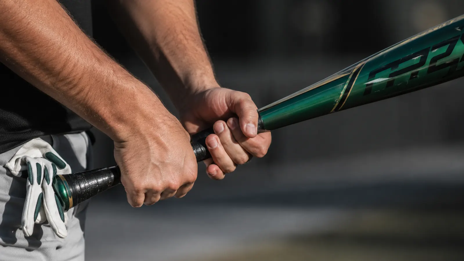 Hands gripping the Louisville Slugger Meta bat handle showing worn grip tape