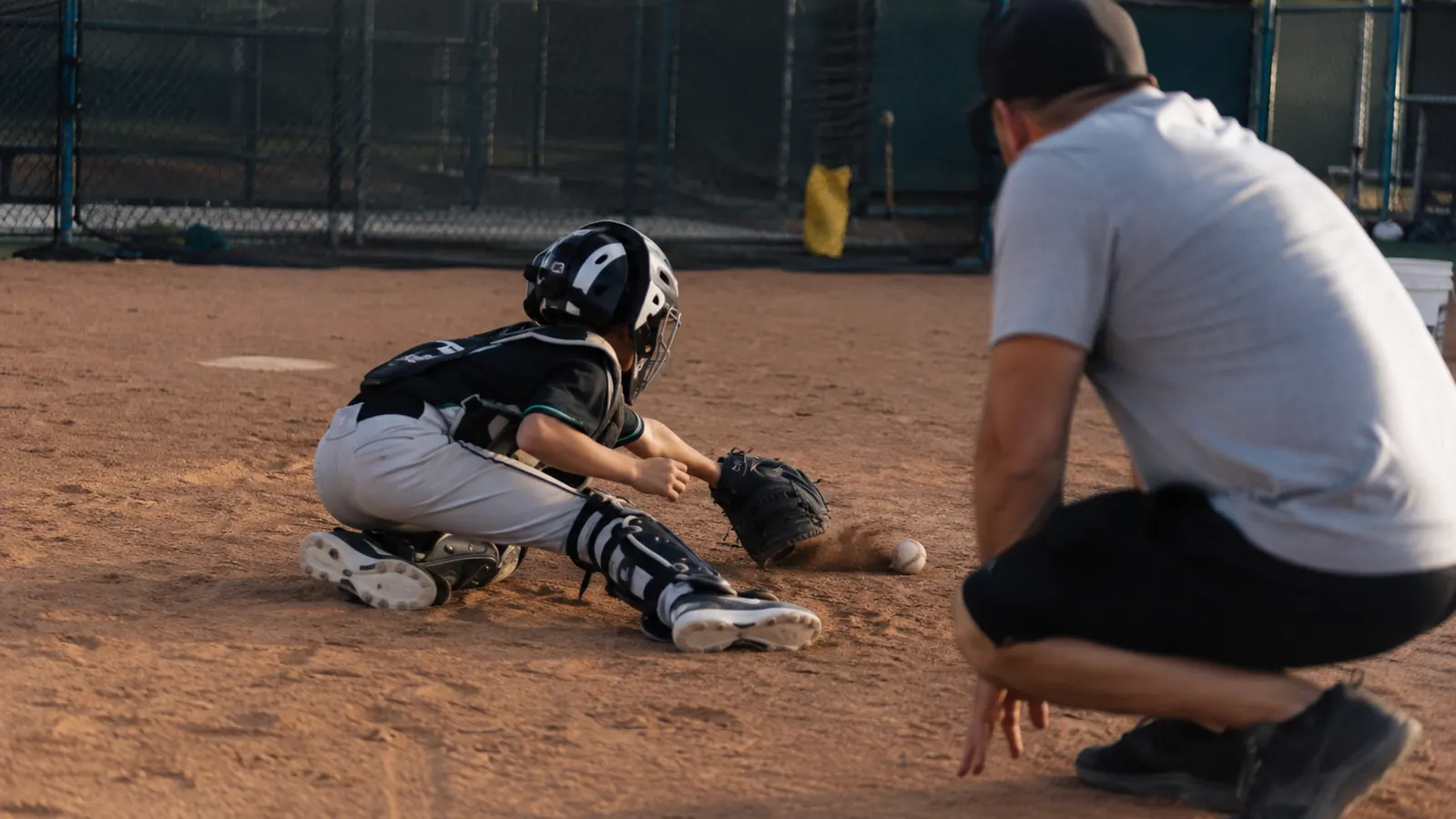 Youth catcher blocking a low pitch in the dirt during a practice bullpen session